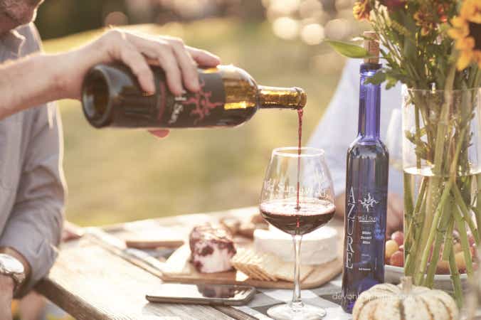 man pouring a glass of wild sun wine outside at the winery