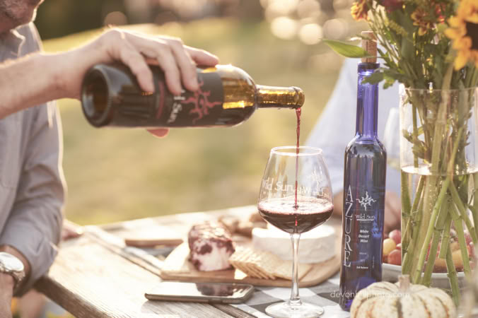 man pouring a glass of wild sun wine outside at the winery